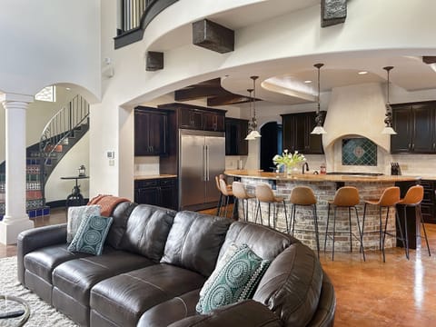 "Welcome to the heart of the house! This spacious living room boasts over 20-foot ceilings, abundant seating, a cozy fireplace, and a smart TV—all with stunning views of the resort-style pool.