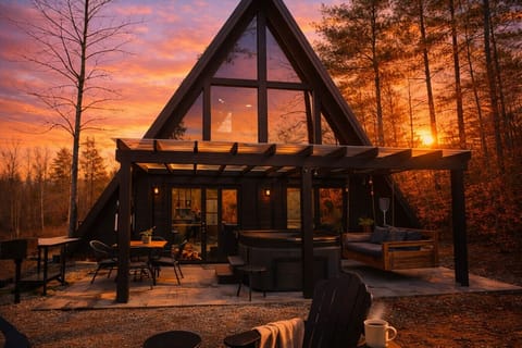 A stunning A-frame retreat featuring a hot tub, covered patio, and peaceful forest setting