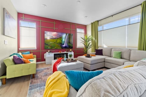 Inviting living room with a comfortable sectional, an 85-inch smart TV, and a cozy fireplace for a perfect gathering space.