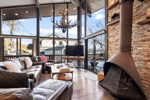 - Living room with floor to ceiling windows showcasing mountain scenery  
- Leather seating and rustic fireplace create a warm inviting atmosphere  
- Large TV and cozy accents make this space perfect for relaxing evenings