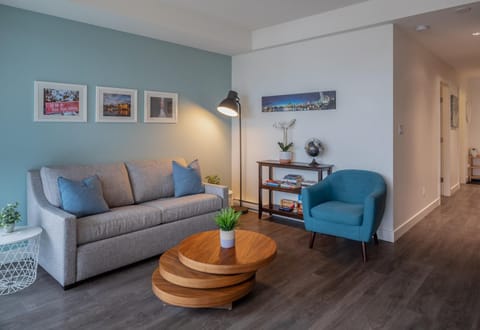 Welcome to your cozy city retreat! Relax in this open-concept main living room featuring full-height windows and sofa seating.