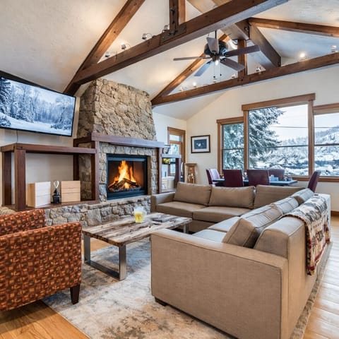 Unwind in this stunning great room with a stone fireplace, vaulted ceilings, and large windows with picturesque mountain views. The perfect Park City escape.