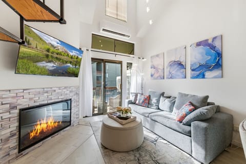 Living room with electric fireplace, and balcony with view of Park City Resort.