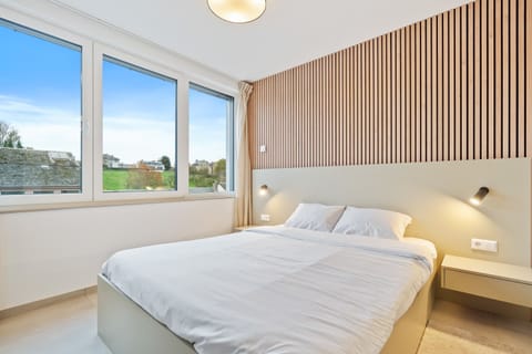 Inviting Living and Sleeping Space – Unwind in a cozy area featuring a queen-sized bed and a sophisticated wooden accent wall.
