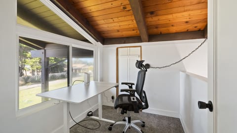 Office area with adjustable height desk and comfy chair overlooking ocean
