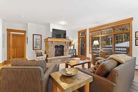 Sink into plush sofas by your crackling stone fireplace, where warm wood tones and mountain views create the perfect retreat.
