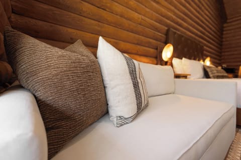 Unwind in the ADA King Room on a plush, stylish couch adorned with cozy, textured throw pillows, offering a perfect spot to relax after a day of adventure.