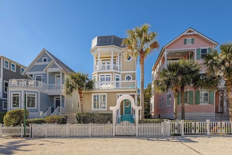 Colorful multi-story beachside property with palm trees and fence