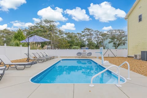 Pool area with lounge chairs, a basketball hoop for kids, and a dining area.