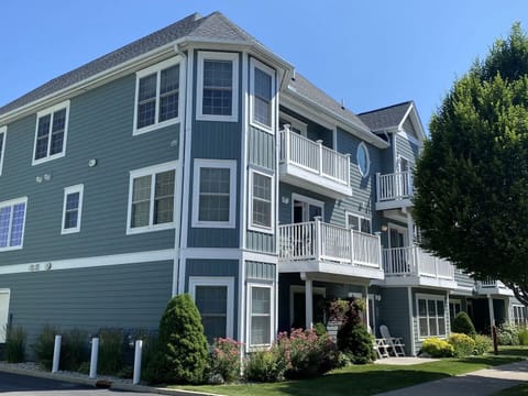 Beautiful exterior view with classic blue siding, white balconies, manicured landscaping, and a welcoming resort-style feel.