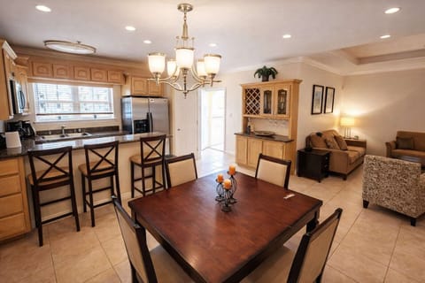 Bright open-concept kitchen & living area with granite counters, stainless appliances, dining for 4, and cozy seating—perfect for relaxing after beach days or family meals.