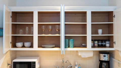 Upper kitchen cabinets stocked with glasses, bowls, plates, mugs, and coffee essentials—everything needed for a comfortable and convenient stay. Begin your mornings with ease and enjoy meals with all the necessities provided.