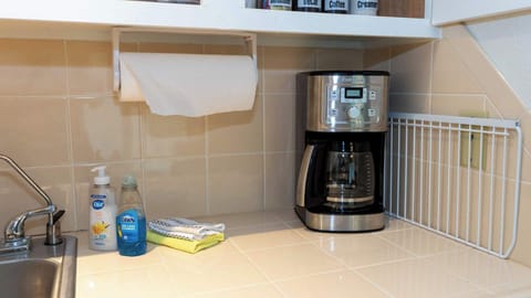 Wake up to fresh coffee with this convenient coffee station, complete with a modern brewer, paper towels, soaps, and essentials—everything needed for easy mornings in your cozy coastal retreat.