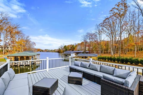 Spacious outdoor deck with comfortable seating, lounge chairs, and scenic views of a wooded area and water.