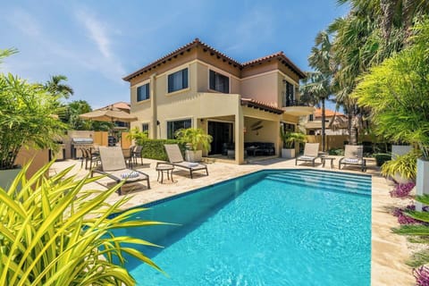 Sunny poolside retreat with cozy lounge chairs, lush greenery, and a beautiful villa backdrop.
