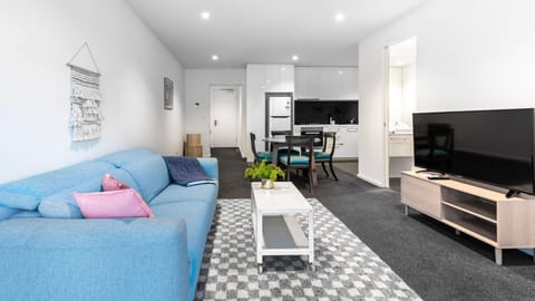 A vibrant blue sofa brings a pop of personality to this bright, open-concept living and entertainment space.