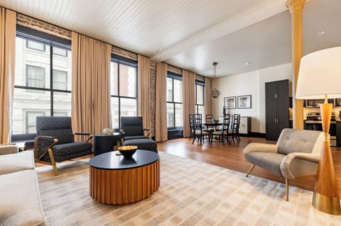 Bright and spacious living area with exposed brick walls and floor-to-ceiling windows, combining historic charm with modern comfort.