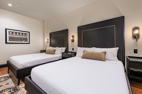 Bedroom 1 - Double queen beds featuring a built-in wardrobe, flat-screen TV, and en-suite bathroom.