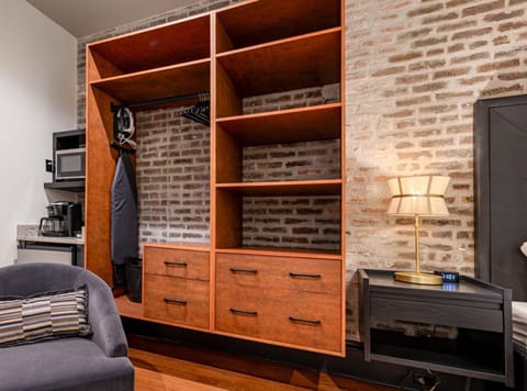 Closet space stocked with hangers, laundry hamper, and iron with ironing board.