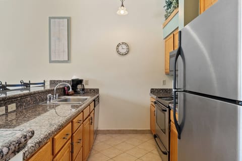 Full kitchen featuring stainless steel appliances, granite countertops, and breakfast bar seating three.