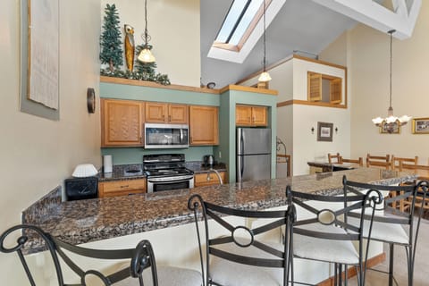 Full kitchen featuring stainless steel appliances, granite countertops, and breakfast bar seating three.