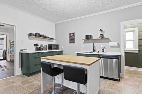 Stylish full kitchen featuring a long table with a chair, sink with faucet, microwave, cozy flooring, and a functional divider leading to the dining area—combining practicality and modern elegance for a warm, inviting space