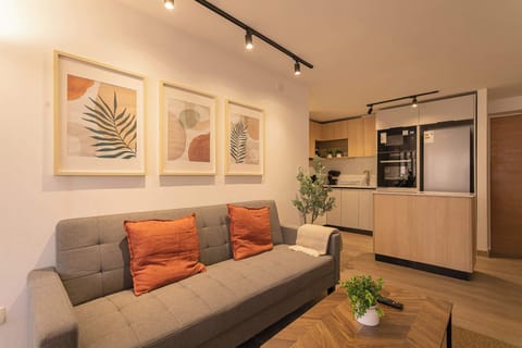 Relax in this stylish living area with modern decor, cozy seating, and a sleek open kitchen—perfect for unwinding or entertaining.