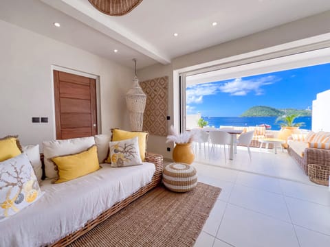 Bright living room with tropical decor, sunny terrace, and panoramic ocean views.