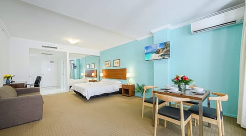 Wide view of the studio showcasing both the king-size bed  along with dining area and air conditioning.