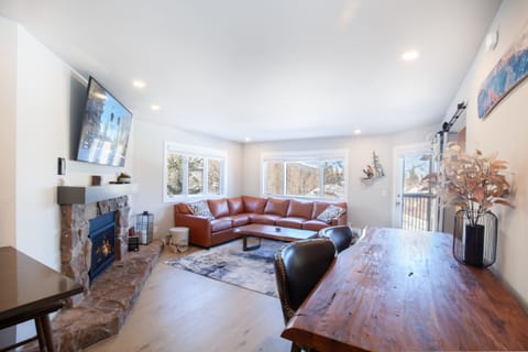 Open floor plan living room has a fireplace with mountain and ski trail views