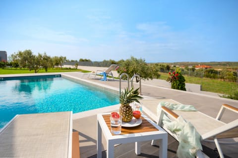 Sunny pool patio with surrounding countryside and sea views