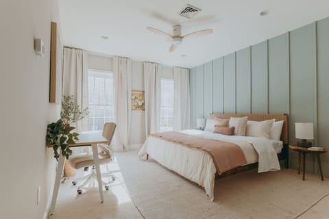 Minimalist bedroom with bedding, pillows, large windows with curtains, and a study table