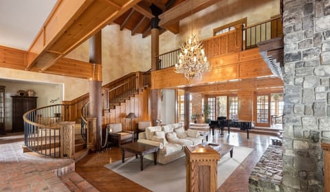 The sweeping grand staircase descends gracefully into the main living room, creating a dramatic focal point and seamlessly connecting the lodge’s elegant spaces.