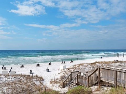 Pristine white sand beach with turquoise waters and wooden boardwalk access, perfect for peaceful coastal getaways.