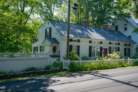 The 1825 home from River Street with white picket fence and lush summer greenery