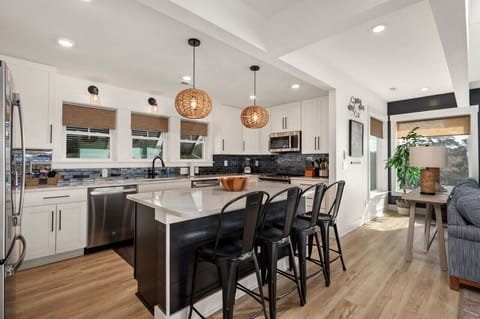 Modern kitchen w/ large island, bar seating & clean finishes ideal for group cooking.