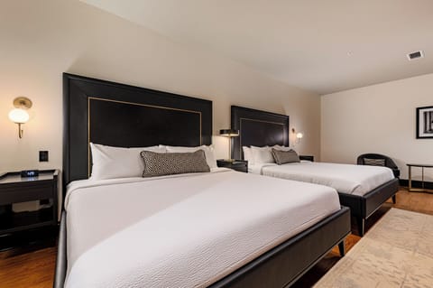 Bedroom 1 - Double king beds featuring a built-in wardrobe, flat-screen TV, and additional seating.