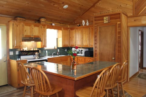 Kitchen with stove, fridge and microwave and bar that seats 5.