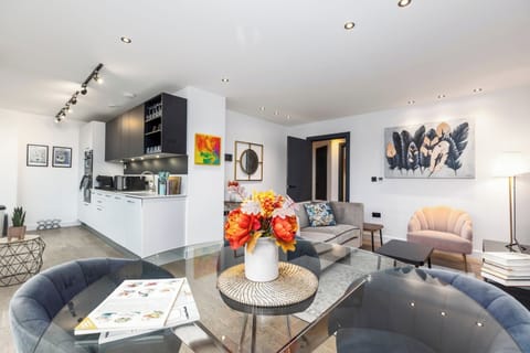 Open-plan living room and kitchen with a TV area and access to a private balcony with chairs.