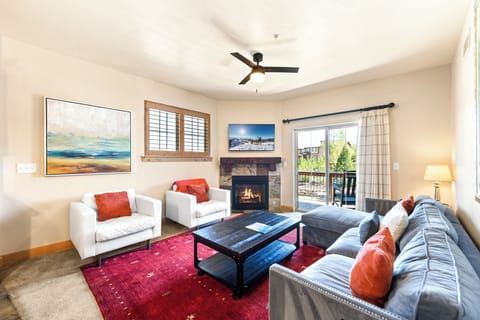 Relax in the inviting living room featuring comfortable seating, a cozy gas fireplace, Smart TV, and private balcony access with mountain views.