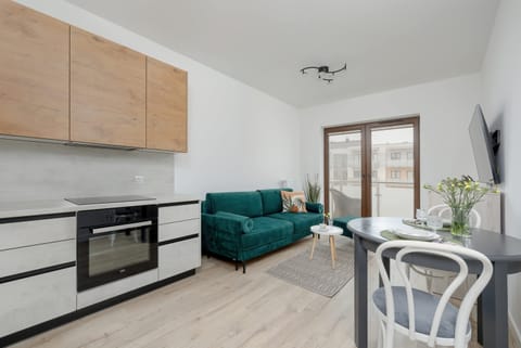 A modern kitchen with wooden cabinets and built-in appliances. A dining table with chairs is placed conveniently nearby.