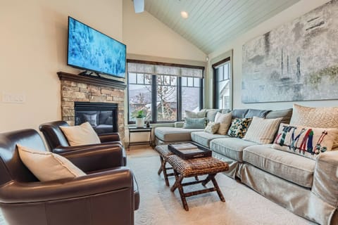 Relax by the cozy stone fireplace in this sun-filled, vaulted living room with a large sectional and two leather chairs. The perfect spot to unwind and stream your favorite shows.