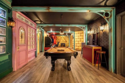 Enter a vibrant game room with a classic pool table, enhanced by charming pink and deep red decor. Rustic details and stylish lighting set a playful mood for unforgettable evenings filled with fun and laughter.