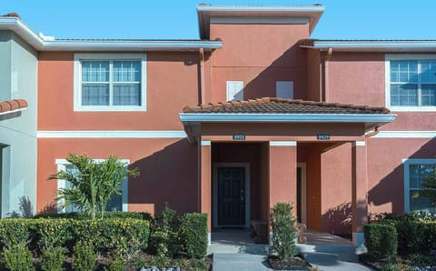 Experience a charming exterior with warm terracotta and soft green tones, enhanced by lush landscaping. The inviting entryway, surrounded by vibrant plants, creates a welcoming atmosphere for your delightful stay.