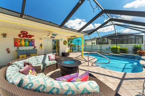 Margaritaville lanai with pool, plenty of seating, bar, firepit, and night lighting.