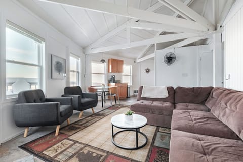 Spacious great room with vaulted exposed beams, a large sectional, and comfy lounge chairs. Bright open layout with mountain views and easy flow to the dining area and kitchen.