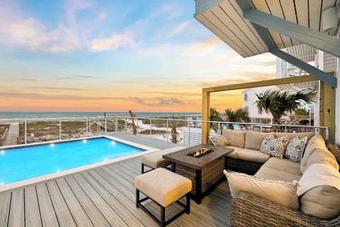 A stunning beachfront property featuring a private pool and outdoor lounge area, with direct coastal access and panoramic ocean views at golden hour.