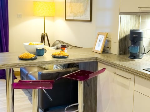 A fully equipped modern kitchen with a breakfast bar and coffee machine