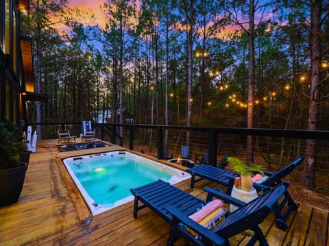 Unwind in the swim spa under string lights, surrounded by peaceful forest views
