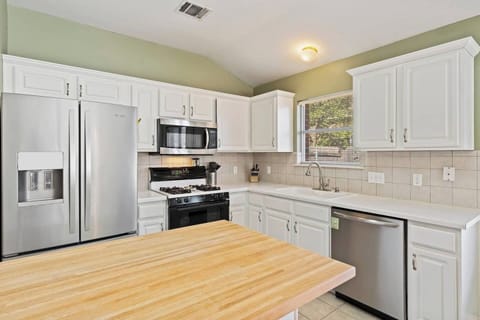 Bright white kitchen with modern appliances and butcher-block counters